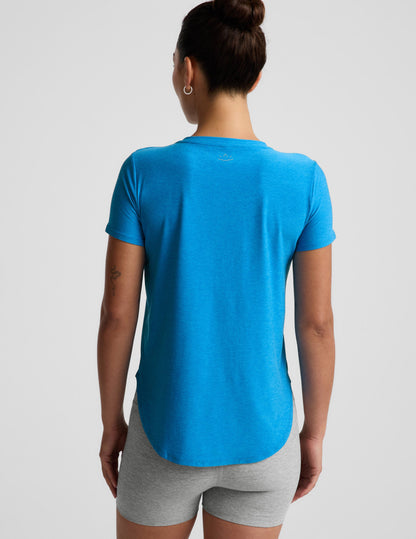 Woman wearing a blue t-shirt and gray biker shorts against a plain background.