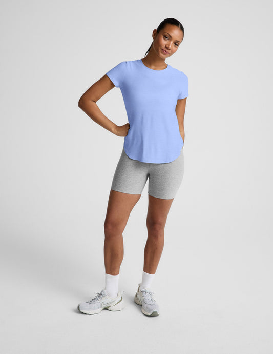 Woman wearing a light blue t-shirt and gray biker shorts against a plain background.