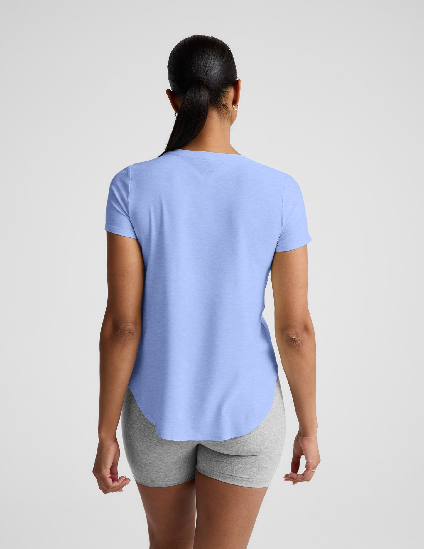 Woman wearing a light blue t-shirt and gray biker shorts against a plain background.