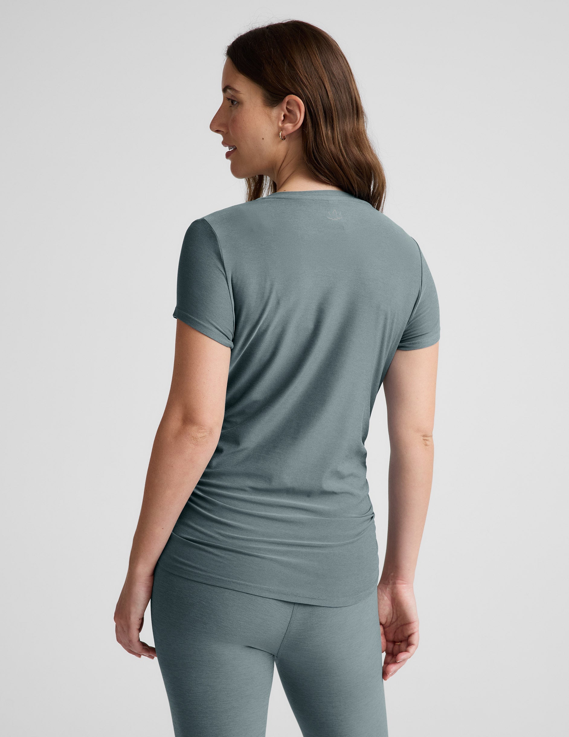 Woman wearing a gray athletic outfit on a light gray background.