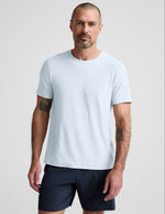 Man wearing a light blue t-shirt and navy shorts on a plain background