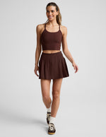 Woman wearing Brown Score™ Pleated Skirt with stitch down front pleats, paired with a matching cropped tank and sneakers.