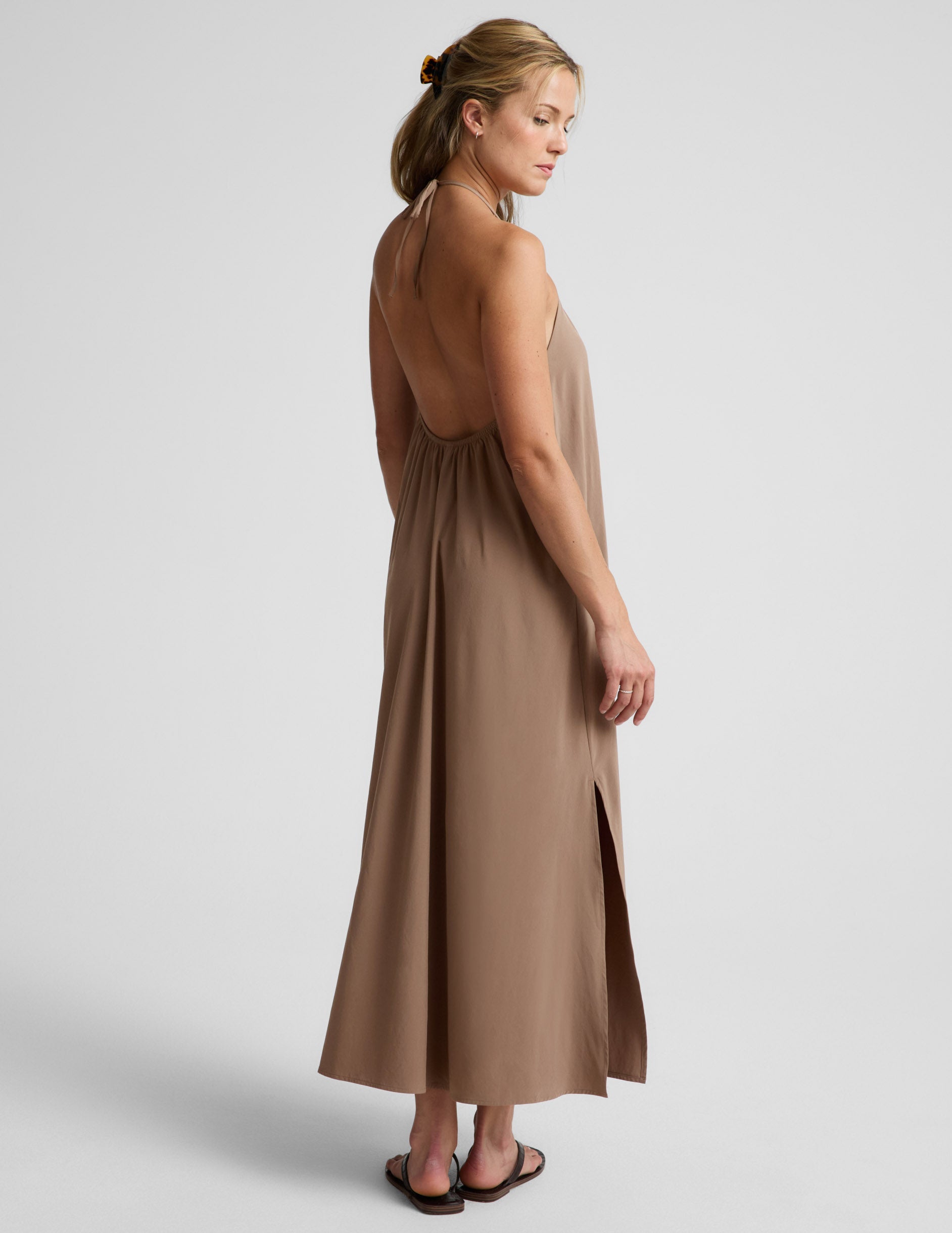 Woman wearing a brown halter maxi dress against a plain background.