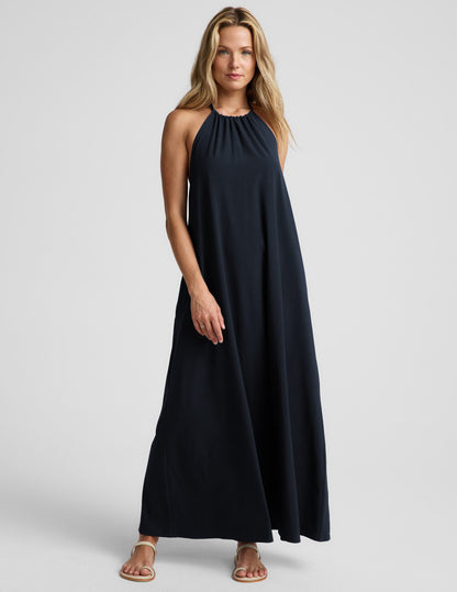 Woman wearing a navy blue halter maxi dress against a plain background.