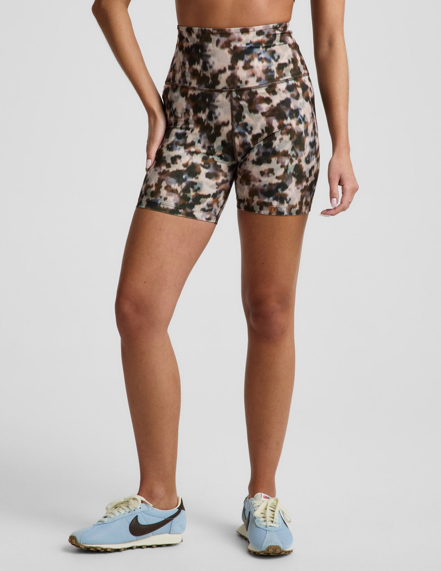 Woman wearing multi-color Dappled Roan SoftMark Keep Pace Biker Short™ with blue sneakers and a high waistband.