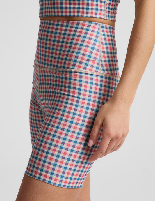 Woman wearing red and blue Sunwashed Gingham SoftMark™ Keep Pace Biker Short with a matching top. Side profile.