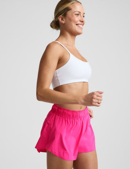 Woman wearing Pink Solemate™ 2.5" Short with a white sports bra. Side profile showing perforated side panels.