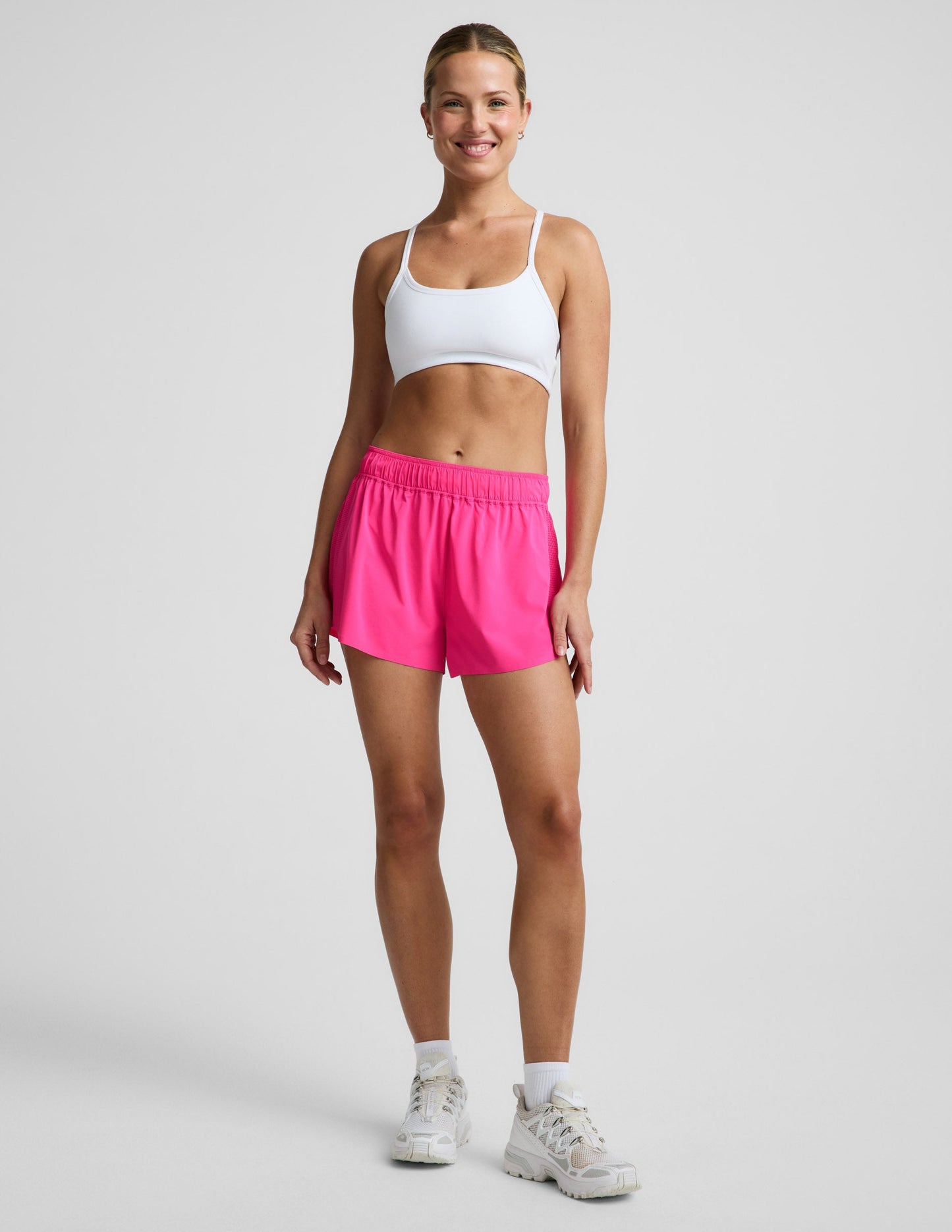 Woman wearing Pink Solemate™ 2.5" Short with a gathered elastic waistband, paired with a white sports bra and sneakers.