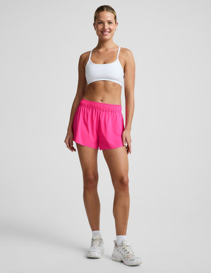 Woman wearing Pink Solemate™ 2.5" Short with a gathered elastic waistband, paired with a white sports bra and sneakers.