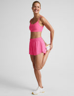 Woman wearing Pink Solemate™ 2.5" Short with a matching pink sports bra and white sneakers in a side profile.