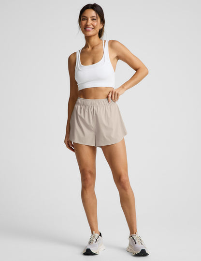 Woman wearing Beige Solemate™ 2.5" Short with a gathered elastic waistband, white sports bra, and cream sneakers.