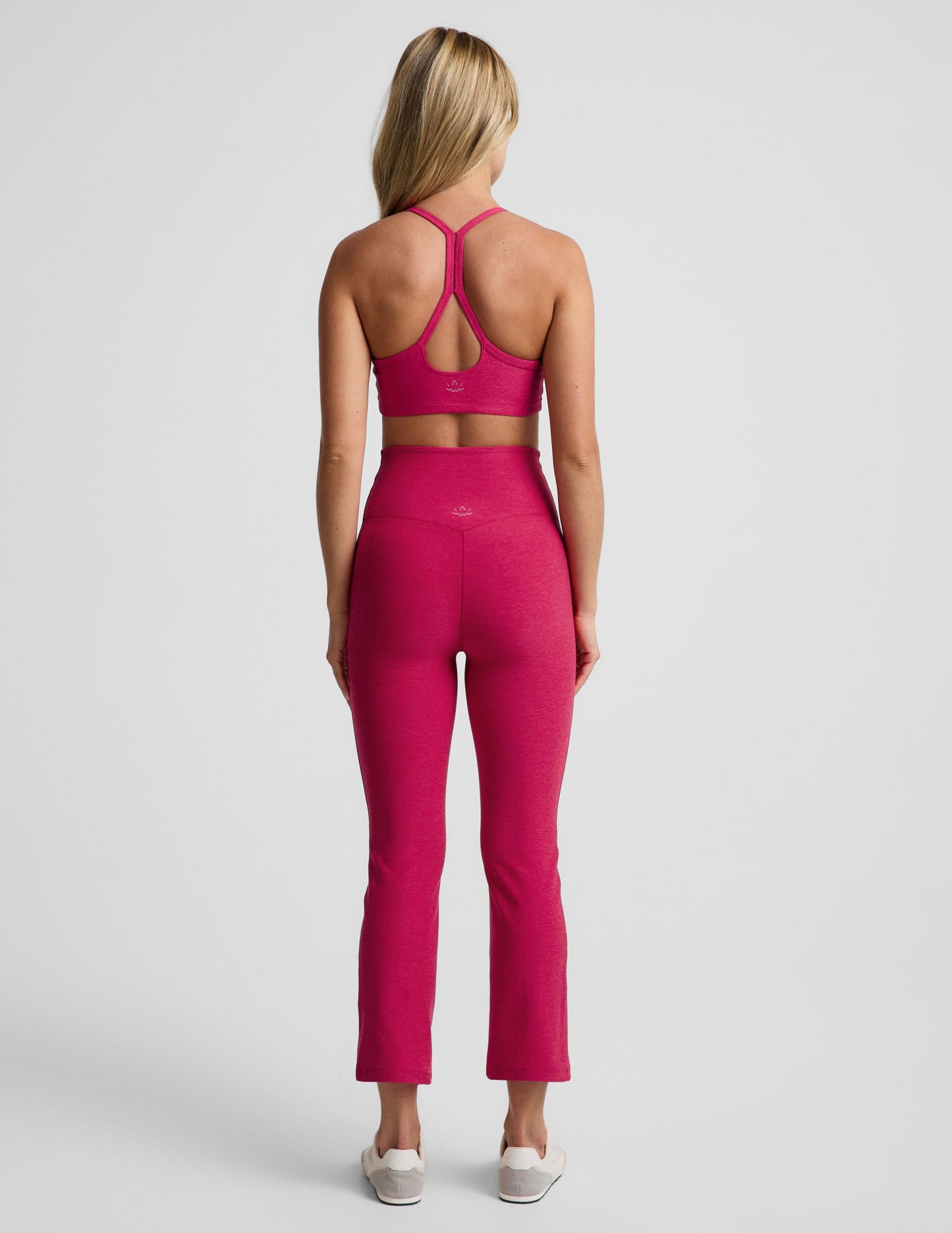 Woman wearing Fuchsia Spacedye™ Pintuck Kick Flare High Waisted Pant, rear view, paired with a matching sports bra.