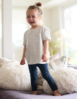 Girl wearing Navy Spacedye™ Toddler Legging paired with a grey short-sleeve t-shirt with a front pocket.
