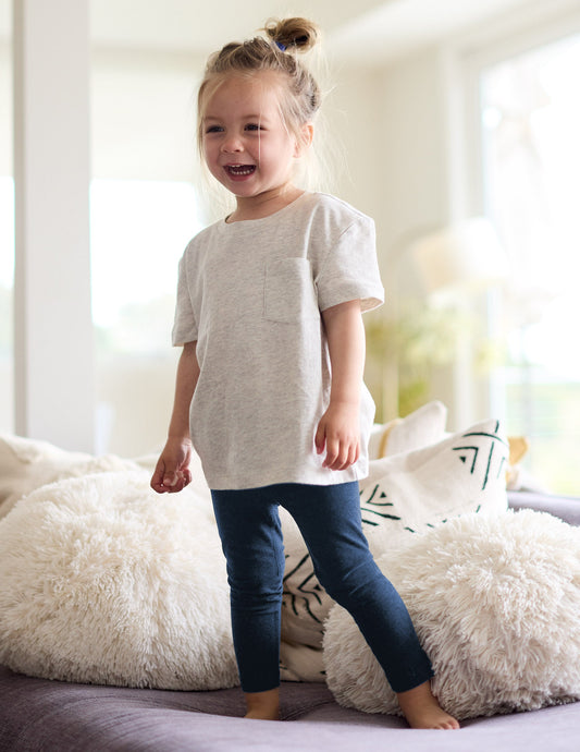 Girl wearing Navy Spacedye™ Toddler Legging paired with a grey short-sleeve t-shirt with a front pocket.