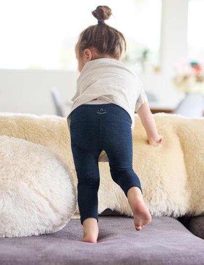 Girl wearing Navy Spacedye™ Toddler Legging paired with a grey t-shirt, rear view.