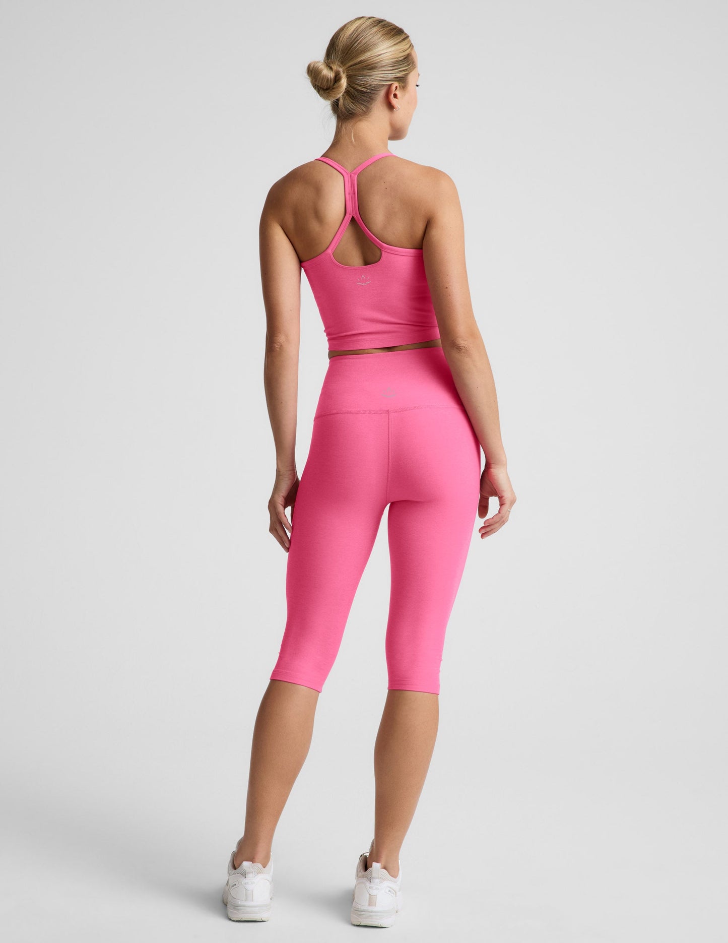 Woman wearing Pink Spacedye Pedal Pusher High Waisted Legging™ paired with a matching tank top and sneakers, rear view.