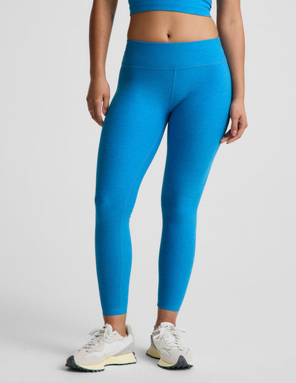 Woman wearing blue mid-rise leggings against a plain background.