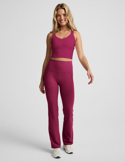 Woman wearing a red cropped tank with a twist cutout back detail and red pants against a plain background.