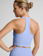 Woman wearing a light blue cropped tank top and leggings against a plain background.