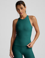 Woman wearing a long length tank and leggings against a plain background.