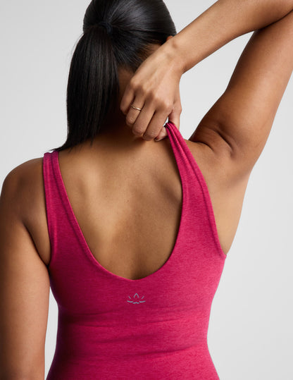 Woman wearing a red tank top and leggings on a light gray background.