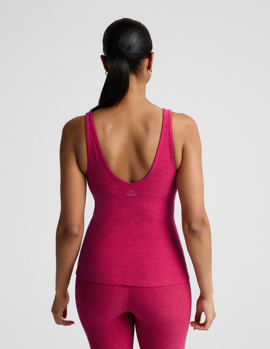 Woman wearing a red tank top and leggings on a light gray background.