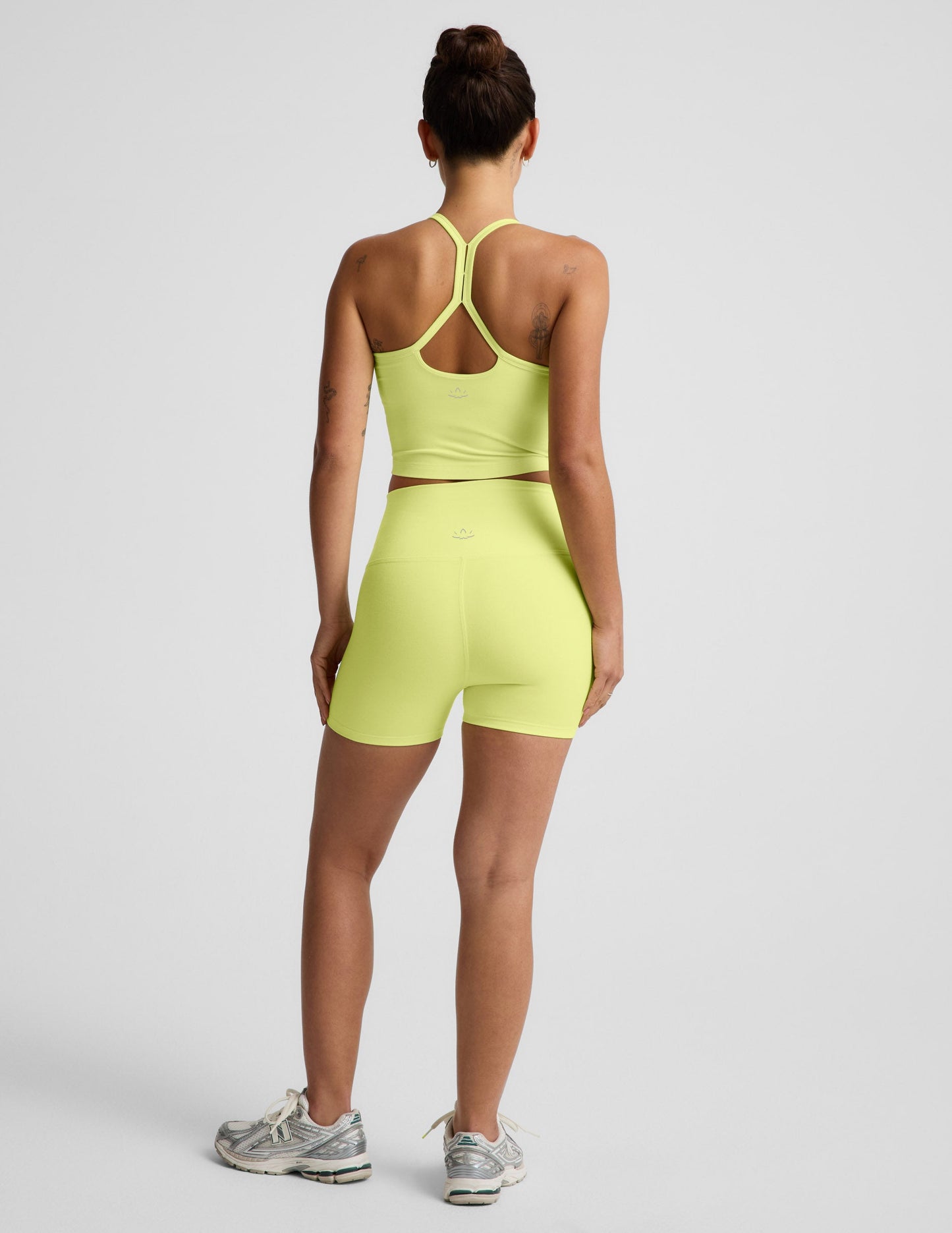 Rear view of woman wearing Yellow Spacedye™ Keep Pace 3" Short with a matching yellow top and silver sneakers.