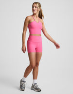 Woman wearing Pink Spacedye™ Keep Pace 3" Short with a matching halter crop top, white socks, and grey sneakers.