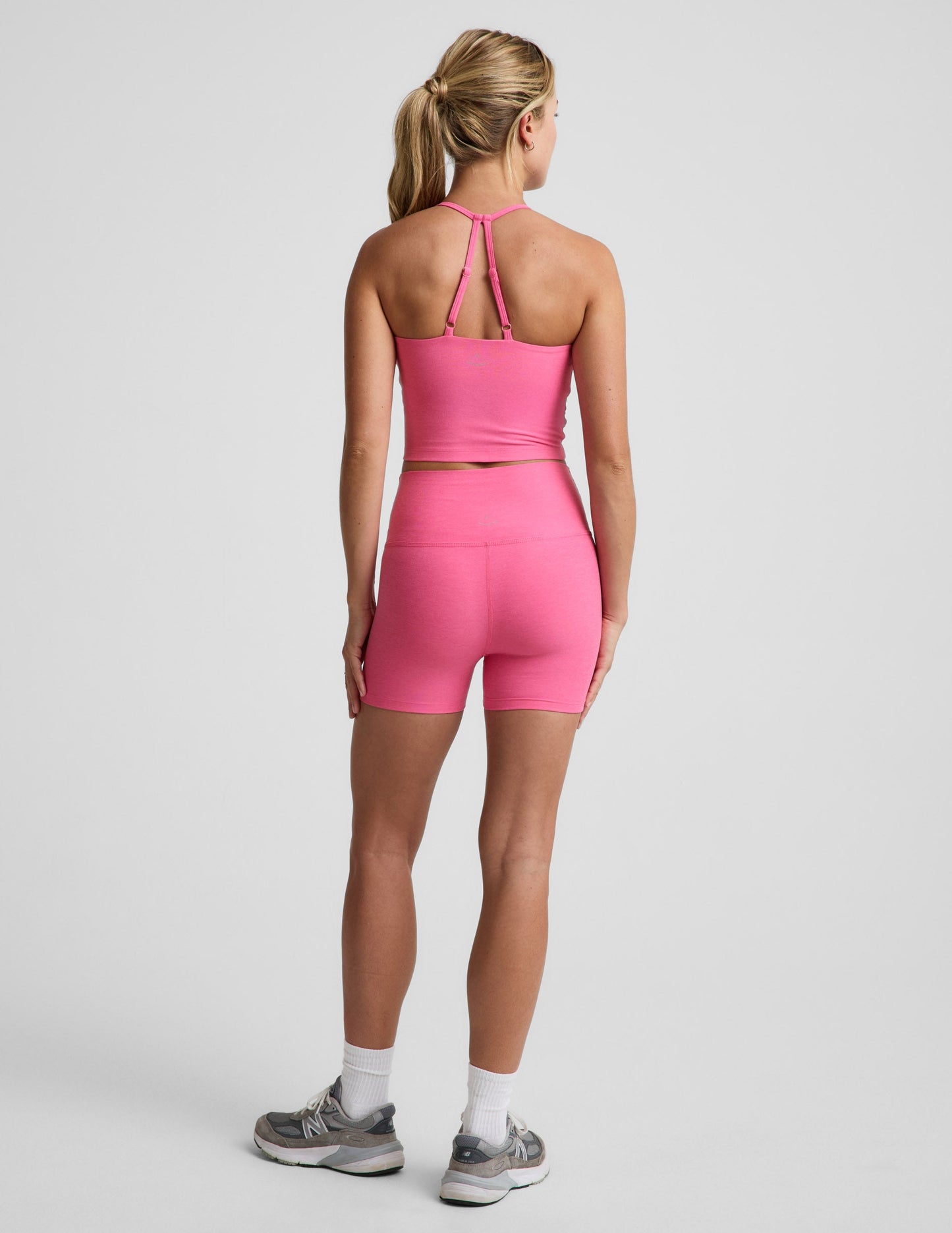 Rear view of woman wearing Pink Spacedye™ Keep Pace 3" Short paired with a matching tank top and grey sneakers.