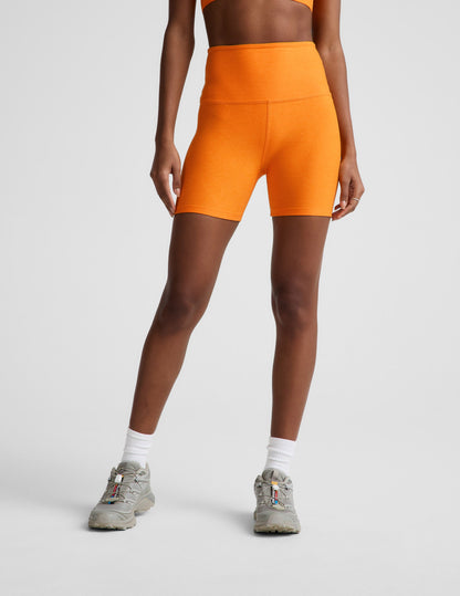 Woman wearing Orange Spacedye™ Keep Pace 5" Biker Short with high waistband, paired with white socks and grey sneakers.