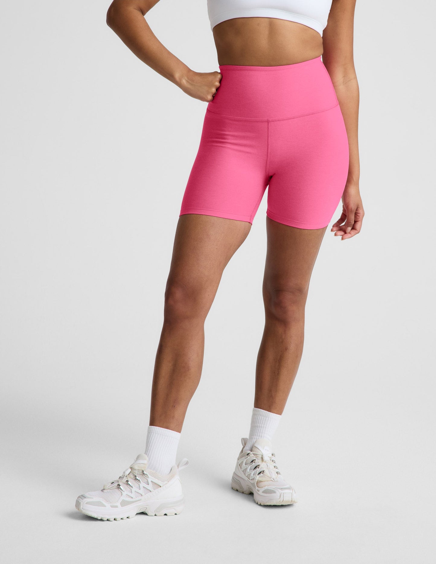 Woman wearing Pink Spacedye™ Keep Pace 5" Biker Short with a high waistband, paired with a white sports bra and sneakers.