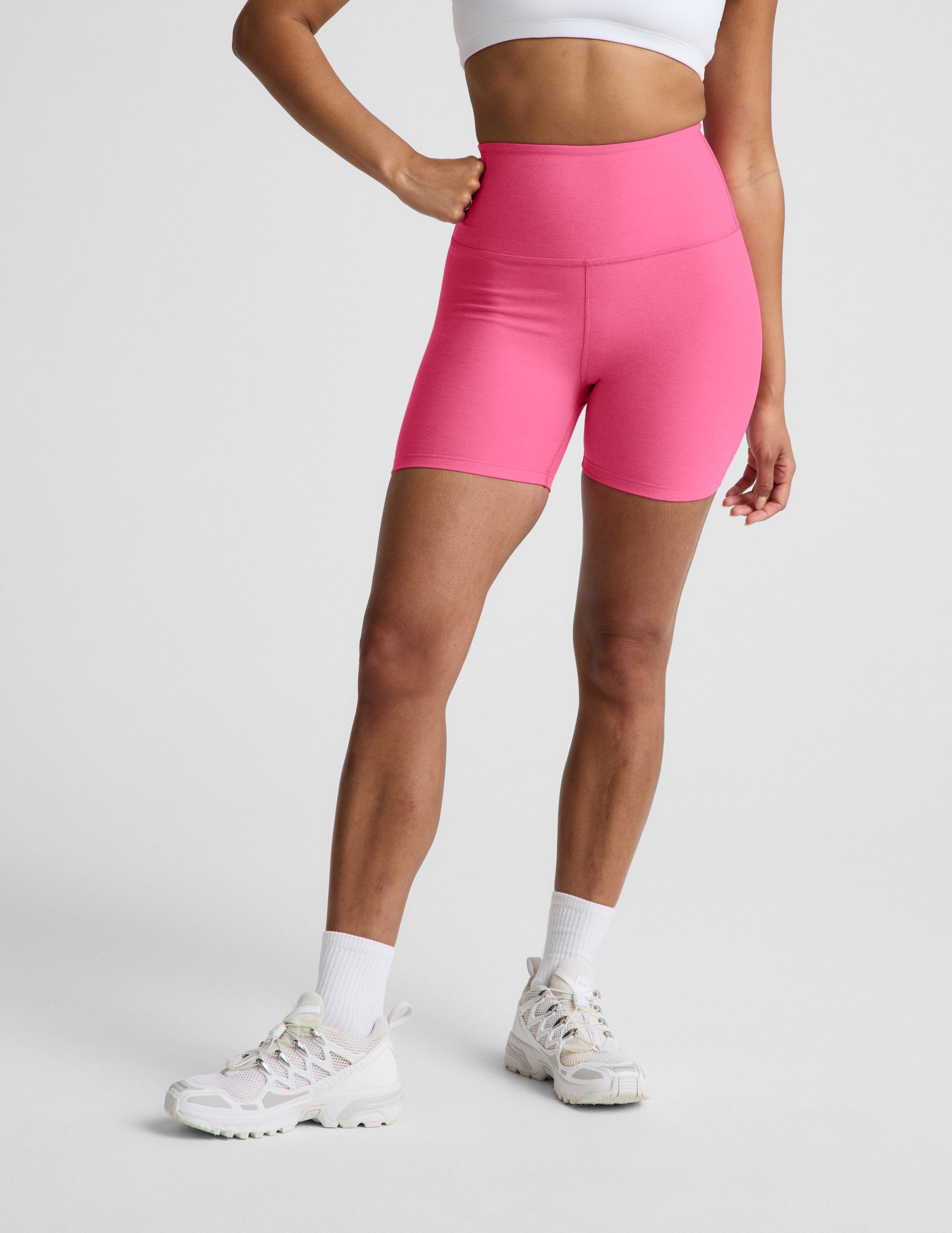 Woman wearing Pink Spacedye™ Keep Pace 5" Biker Short with a high waistband, paired with a white sports bra and sneakers.