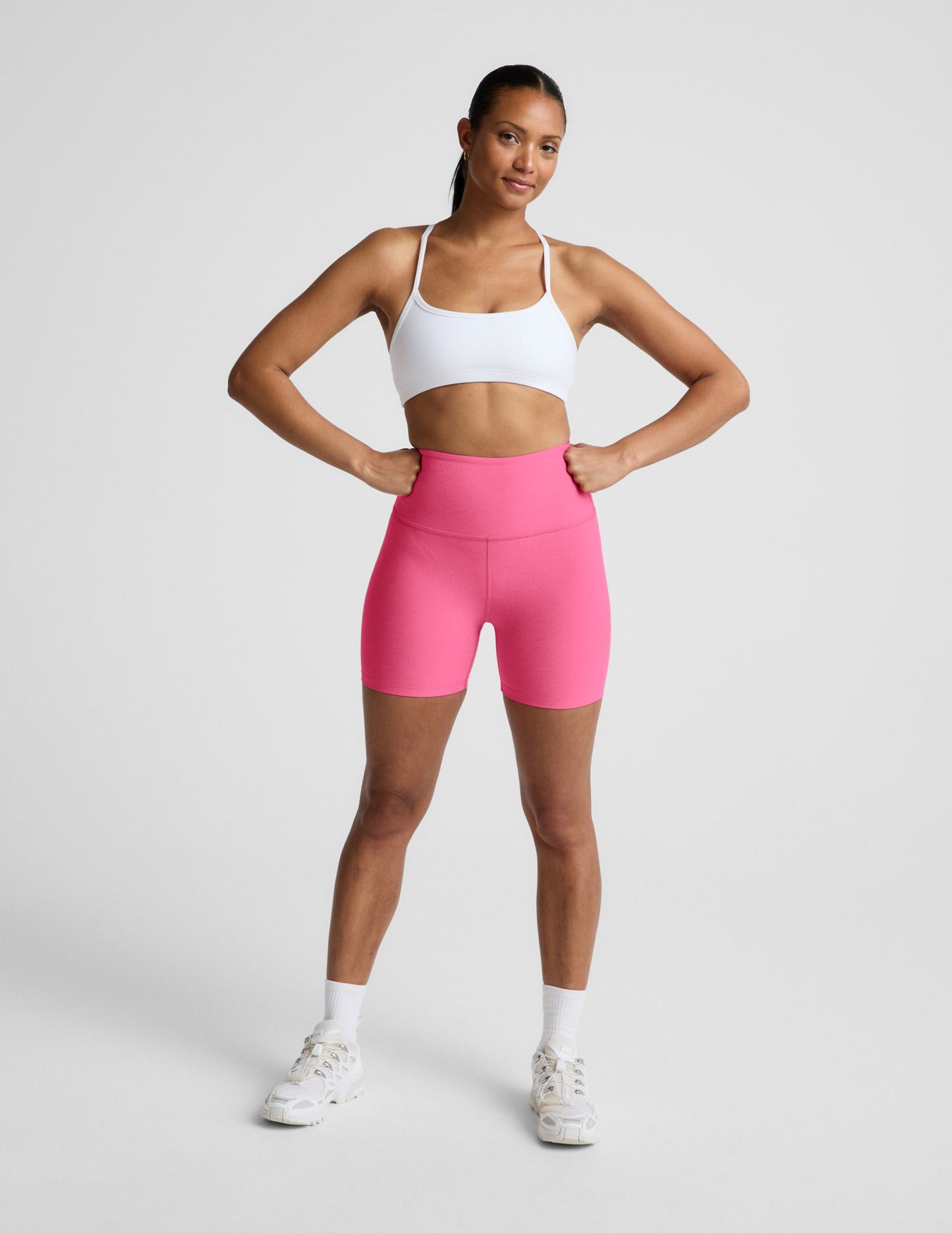 Woman wearing Pink Spacedye™ Keep Pace 5" Biker Short paired with a white sports bra and sneakers.