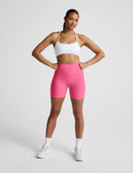 Woman wearing Pink Spacedye™ Keep Pace 5" Biker Short paired with a white sports bra and sneakers.