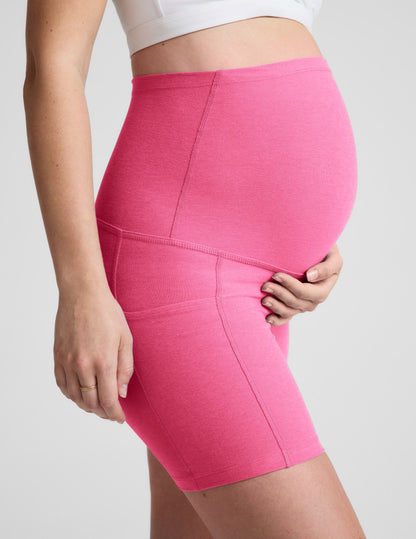 Side profile of woman wearing Pink Spacedye™ Keep Pace 5" Maternity Pocket Biker Short paired with a white top.