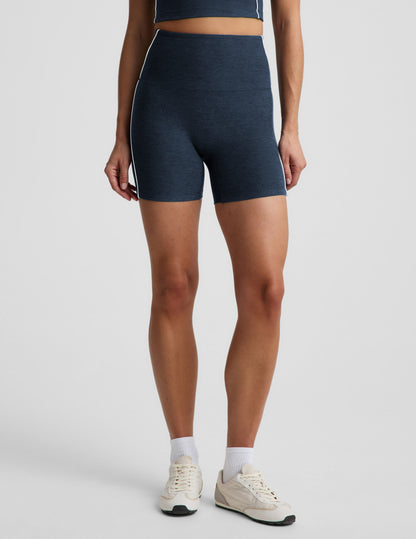 Woman wearing Navy Spacedye™ Streamline 5" Short with side stripes, matching tank, white socks, and cream sneakers.