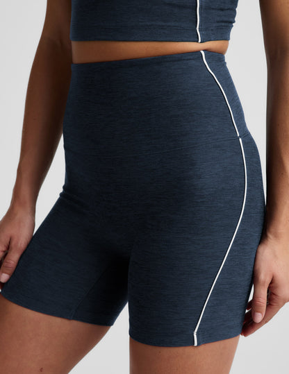 Woman wearing Navy Spacedye™ Streamline 5" Short with a matching tank, featuring high-rise waistband and white side piping.