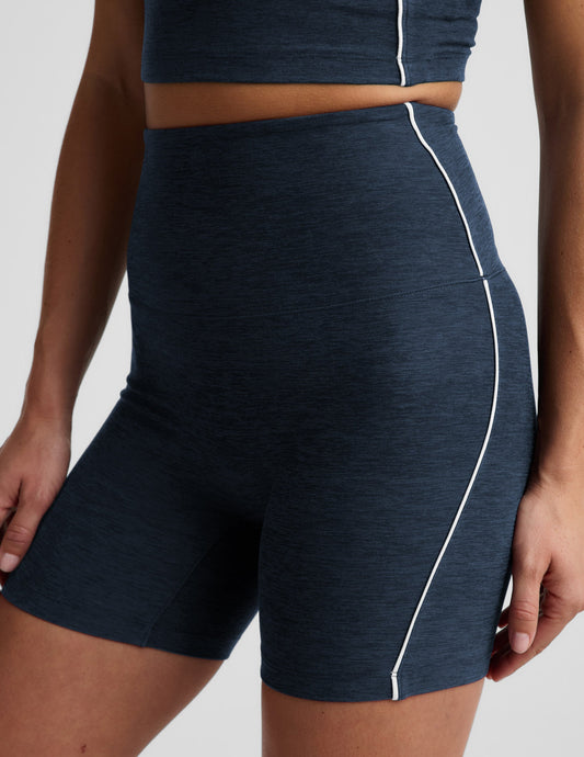 Woman wearing Navy Spacedye™ Streamline 5" Short with a matching tank, featuring high-rise waistband and white side piping.