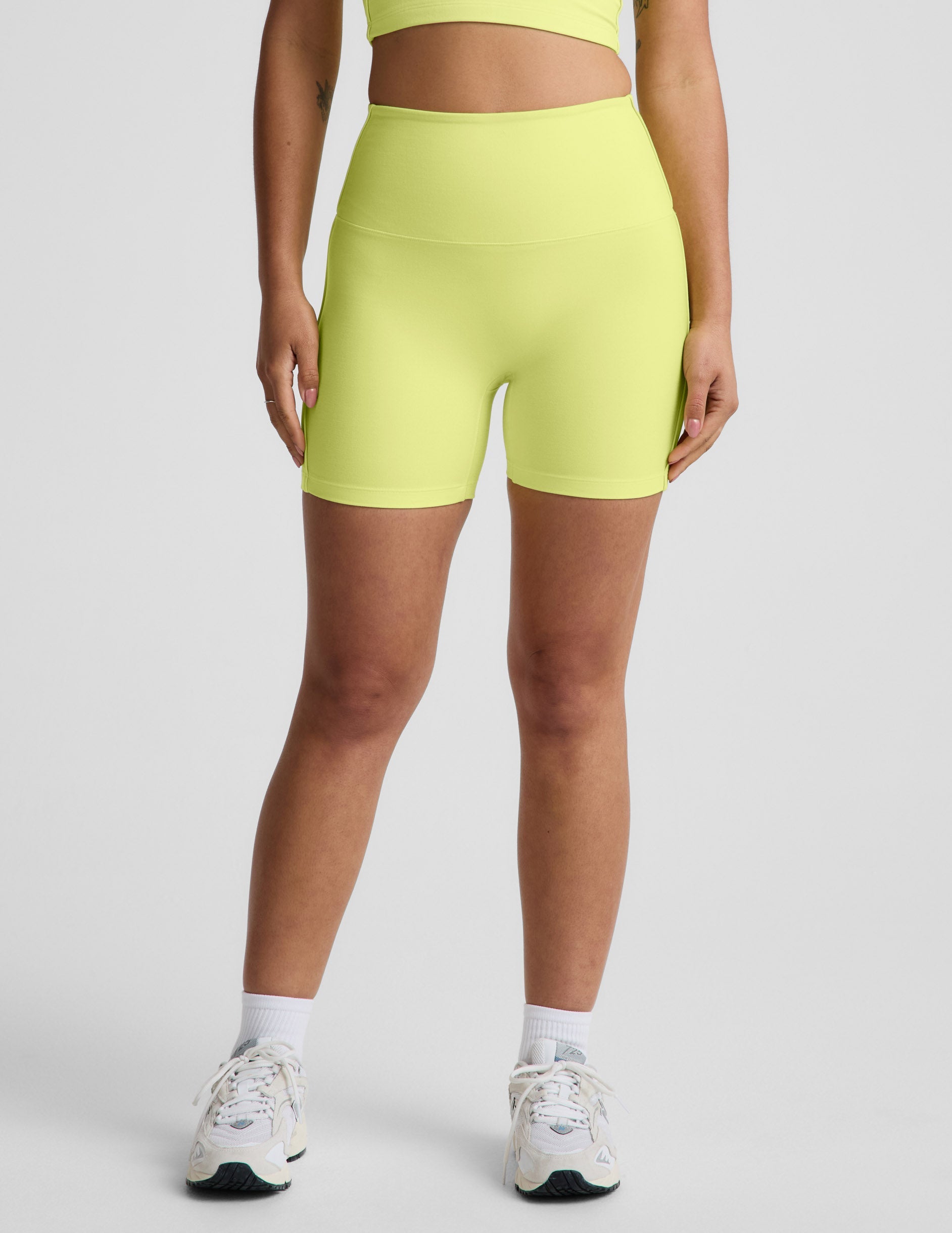 Woman wearing Yellow Spacedye™ Streamline 5" Short with a matching tank top, featuring a high-rise, no front seam design.