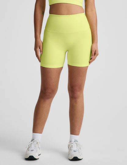 Woman wearing Yellow Spacedye™ Streamline 5" Short with a matching tank top, featuring a high-rise, no front seam design.