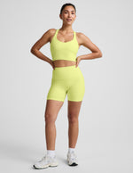 Woman wearing Yellow Spacedye™ Streamline 5" Short with a matching racerback tank and white sneakers.