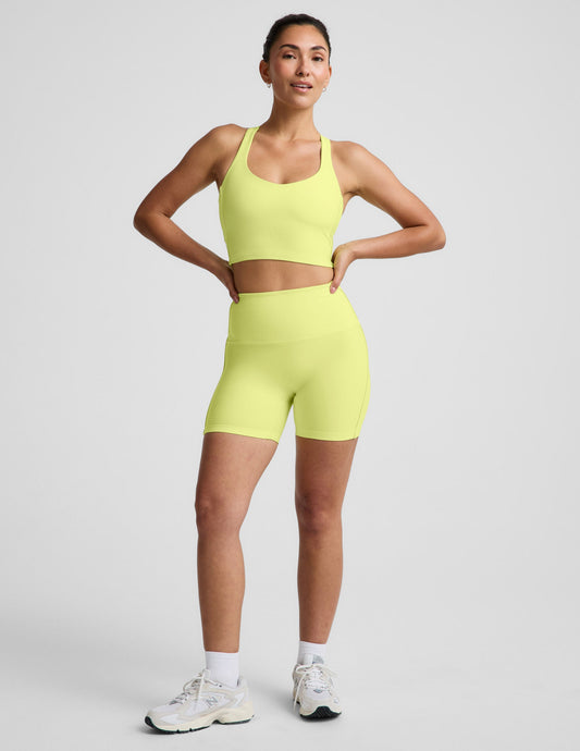 Woman wearing Yellow Spacedye™ Streamline 5" Short with a matching racerback tank and white sneakers.