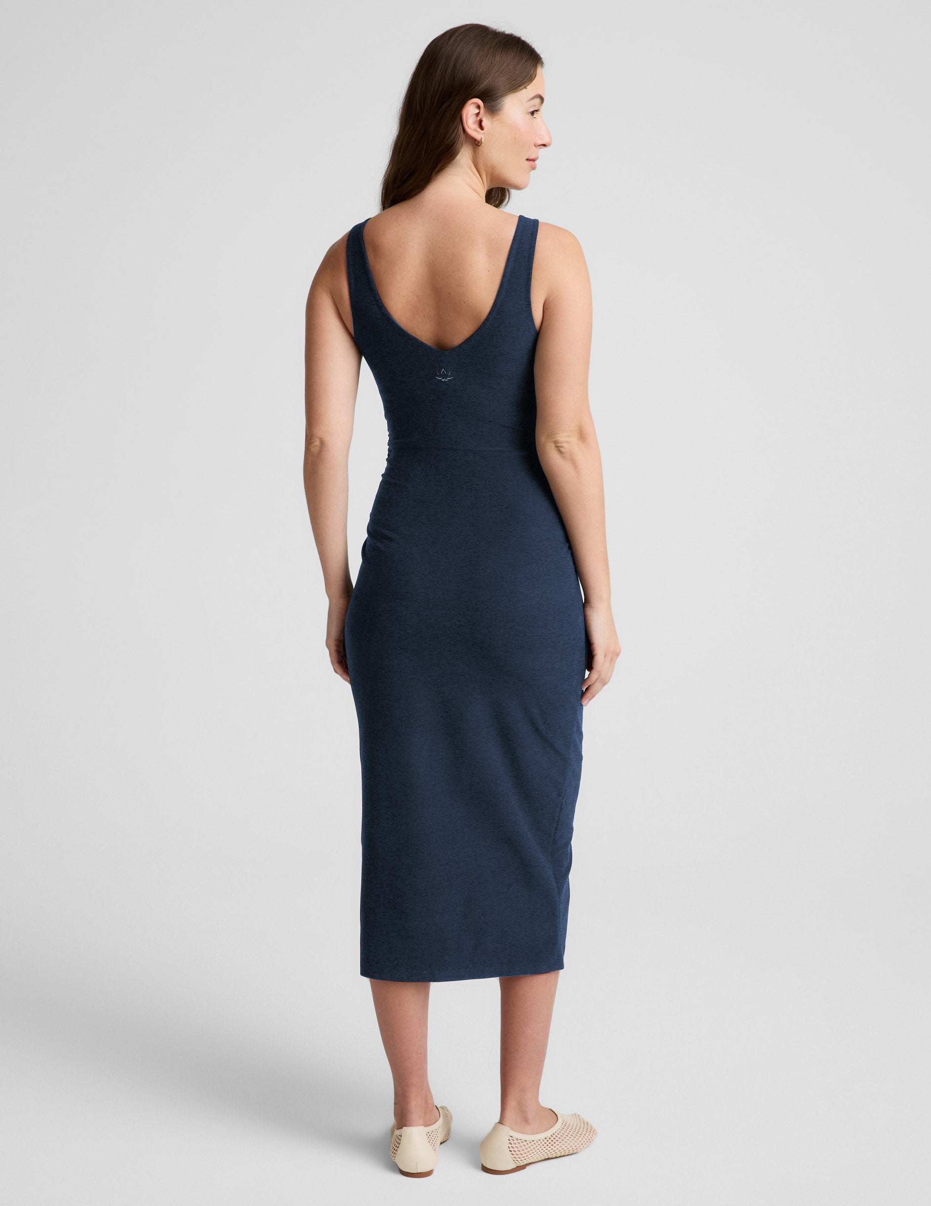 Woman wearing a navy blue sleeveless maternity dress against a light gray background.