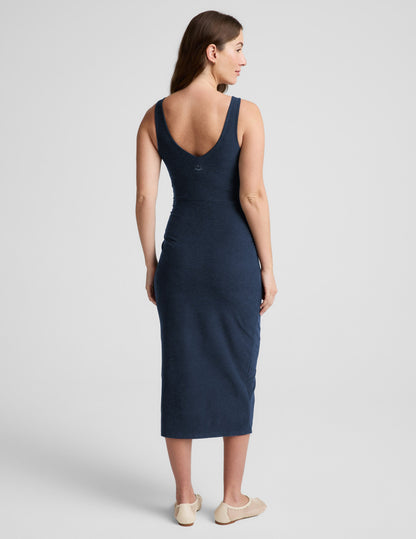 Woman wearing a navy blue sleeveless maternity dress against a light gray background.