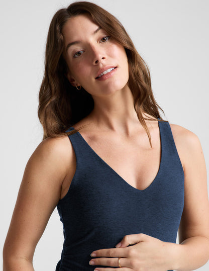Woman wearing a navy blue sleeveless maternity dress against a light gray background.