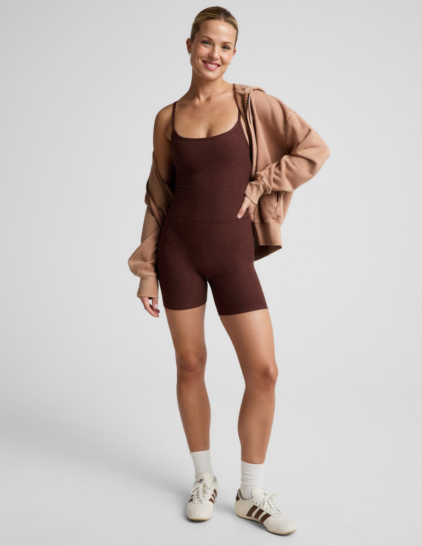 Woman wearing a brown biker jumpsuit against a plain background.