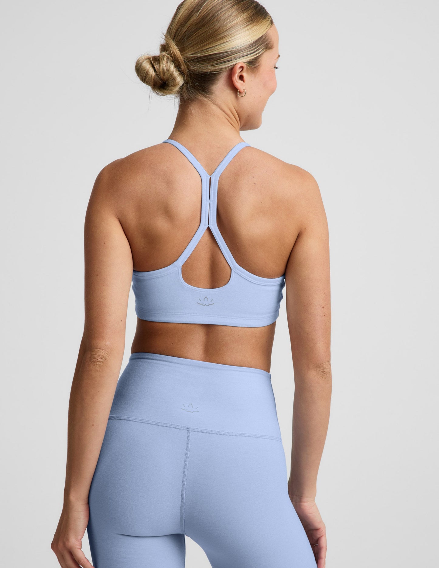Woman wearing a light blue sports bra and biker shorts against a plain background.