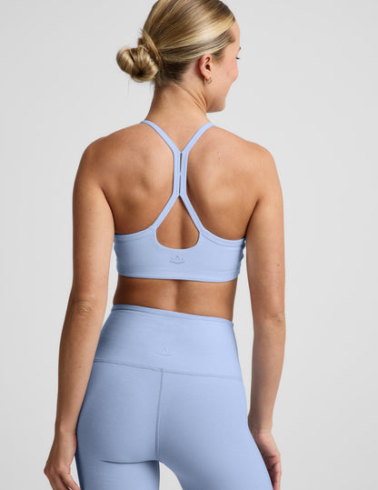 Woman wearing a light blue sports bra and biker shorts against a plain background.