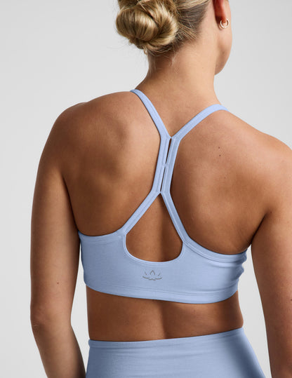 Woman wearing a light blue sports bra and biker shorts against a plain background.