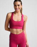 Woman wearing a red bra and leggings against a light gray background.
